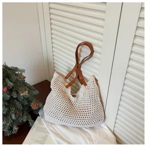Cream crochet beach bag with brown leather straps in a cozy holiday setting