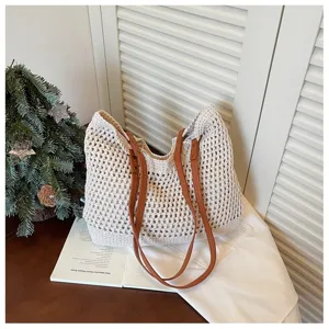 Macro view of beige crochet woven tote bag with brown faux leather handles on table