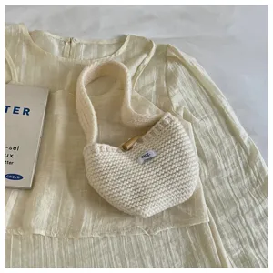 Detailed close-up of a cozy cream knit wool handbag with a wooden toggle button.