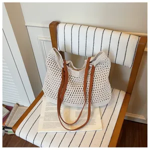 Casual off-white crochet woven beach bag with brown leather straps on a vintage chair