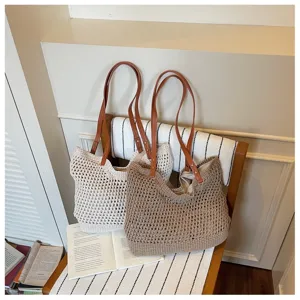 Close-up detail of a hollow crochet beach tote bag featuring brown leather shoulder straps.