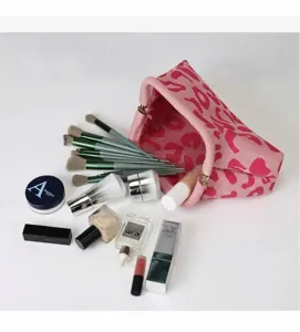 Stijlvolle roze make-uptas met luipaardprint en kwasten op witte achtergrond.