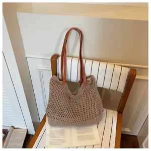 Detailed view of a handmade hollow woven straw beach bag with brown leather shoulder straps