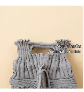 Detail of gray knitted pleated crossbody bag showing the sturdy handle texture
