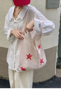 Detail of off-white crochet tote bag featuring red star and cherry patterns