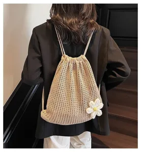 Mochila de ganchillo con cordón y detalle de flor blanca usada por una modelo chic