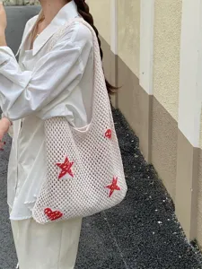 Detailed view of off-white hollow knit tote bag with red star and heart motifs