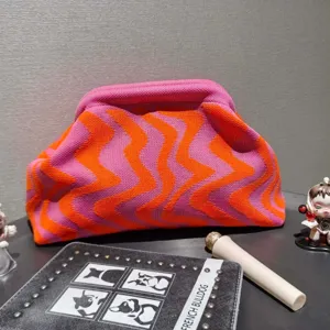 Detailed view of vibrant pink and orange wave pattern knitted clutch and makeup bag