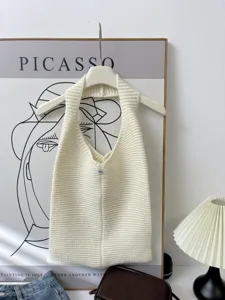 Close-up detail of a white minimalist knitted tote bag with soft texture and small label