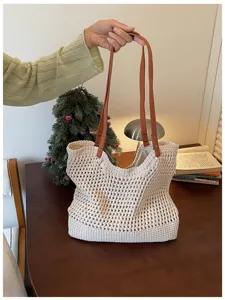 Detail view of a woven cotton mesh tote bag with brown leather-like straps on a table