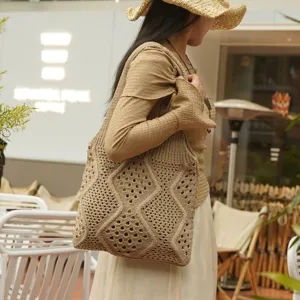 Mujer con un gran bolso tote de punto beige con patrones de diamantes en un café