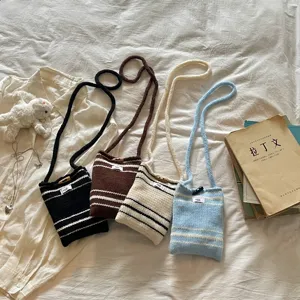 Set mit vier handgefertigten gestreiften Mini-Strickumhängetaschen in verschiedenen Farben.