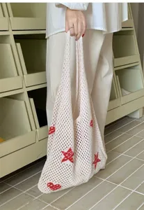 Close-up of cream knit tote bag with red heart patterns for summer beach vacation