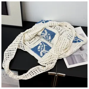 Detailweergave van de crème en blauwe gebreide shopper met gehaakte bloemmotieven