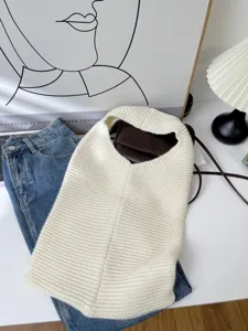 Large capacity cream white knitted tote bag shown in a cozy lifestyle setting with denim jeans