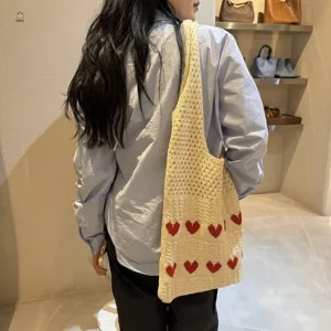 Detailed texture of a cream knitted heart pattern tote bag on a model's shoulder