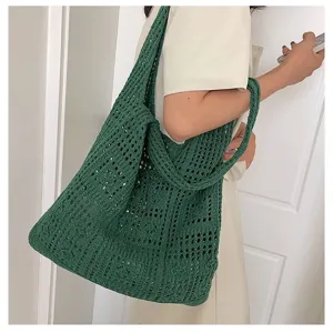 Gros plan d'un sac cabas en maille tricotée verte avec motifs évidés porté par un modèle