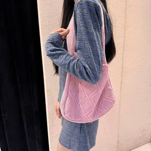 Close-up of pink cable knit tote bag worn by a model in casual setting