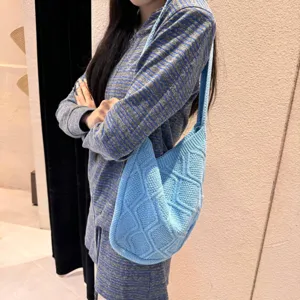 Detail view of a light blue knitted shoulder bag featuring a classic diamond knit pattern