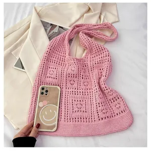 Gros plan d'un sac à bandoulière en crochet rose montrant la texture de tricot vintage
