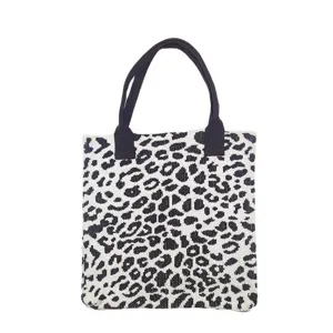 Detailed view of a knitted tote bag with black and white leopard print and black handles