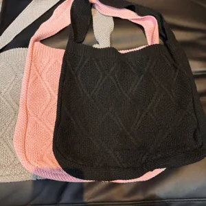Close-up of vintage knitted tote bags with diamond pattern in black, pink, and grey