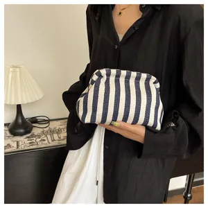 Pochette nuage à rayures bleues et blanches élégante tenue par un mannequin en chemise.