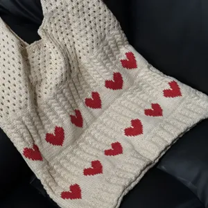 Macro view showing the detailed texture and heart pattern of the knitted tote bag.