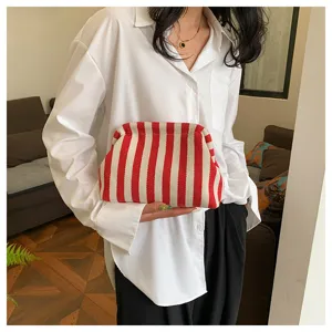 Gros plan d'une pochette nuage rayée rouge et blanc tenue par un mannequin de mode