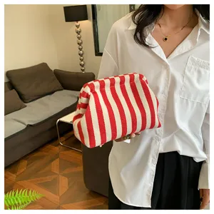 Vue détaillée d'une pochette nuage élégante à rayures rouges et blanches tenue par un modèle.
