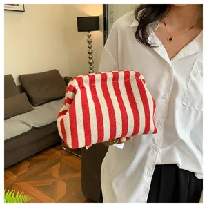 Détail d'une pochette cosmétique à rayures rouges et blanches tenue par un mannequin