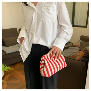 Gros plan d'une pochette nuage élégante à rayures rouges et blanches tenue par un mannequin
