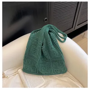 Vue détaillée du sac à bandoulière au crochet vert foncé sur une chaise blanche