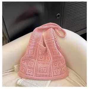 Vue détaillée d'un sac à bandoulière en maille ajourée rose rétro sur un canapé