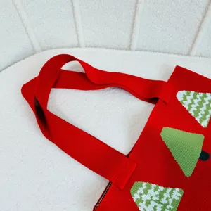 Close-up detail showing the handle and texture of a red Christmas tree knitted shoulder bag.