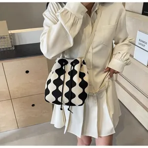Close-up of a knitted bucket bag with black and white wavy pattern and drawstring