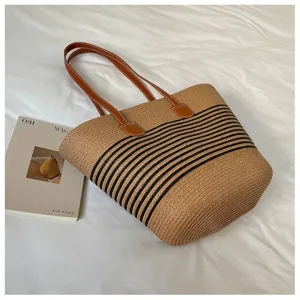 Large woven straw tote bag featuring black stripes and brown faux leather handles