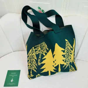 Primer plano de bolso tote de punto verde con árboles de Navidad amarillos en sofá