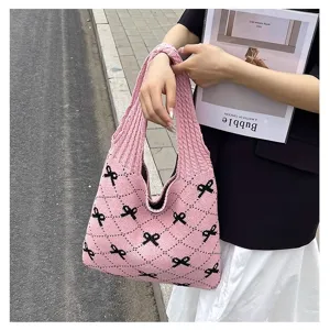 Close-up of pink knitted tote bag with black bow patterns and diamond-grid texture