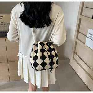 Detail view of a trendy black and white wave pattern knitted bucket bag worn by a model.