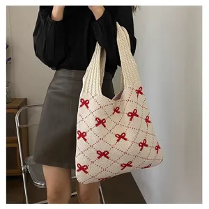 Lifestyle view of a large capacity knitted tote bag with red bow patterns on beige.