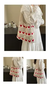 Crochet tote bag with red heart patterns worn by a model in a white eyelet maxi dress