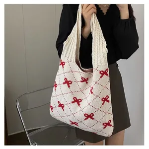 Detail view of a knitted tote bag featuring a red bow pattern and soft weave texture