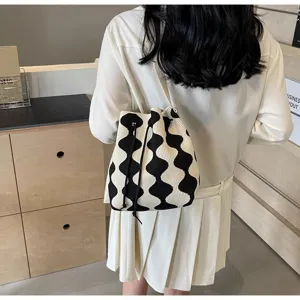 Close-up detail of the black and white wavy pattern on a knitted drawstring bucket bag