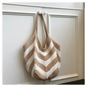 Handmade khaki and white striped crochet shoulder bag hanging on a white cabinet door