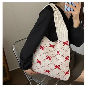Detail showing a knitted tote bag with cute red bowknot patterns carried on shoulder