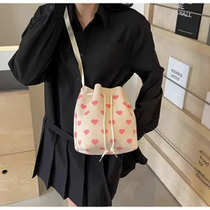 Minimalist cream bucket bag with pink hearts shown on model in a stylish setting
