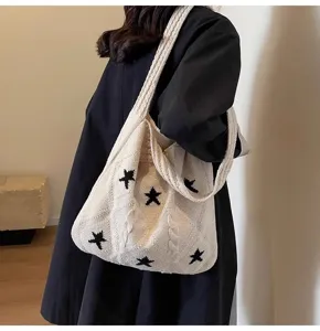 Detailed view of a chic beige knitted shoulder tote bag featuring black star patterns