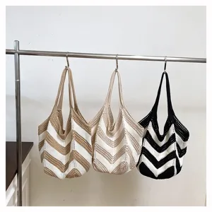 Three large capacity crochet shoulder bags with chevron stripes hanging on a metal rack