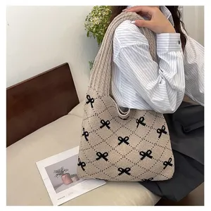 Lifestyle detail view of a beige knitted tote bag with black bow patterns worn on shoulder